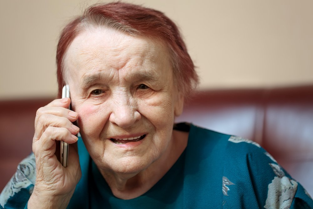 Elderly lady talking on a mobile phone frowning in concentration as she listens to the conversation, close up of her face